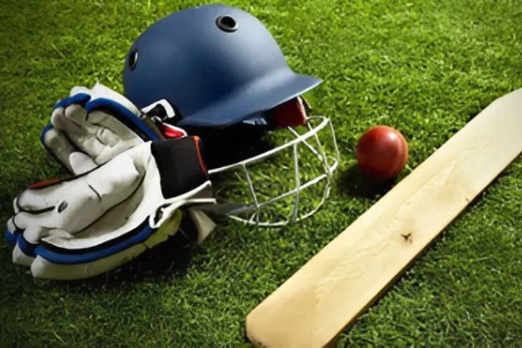 Cricket 2026 - casque, gants, balle rouge et batte de cricket sur l'herbe